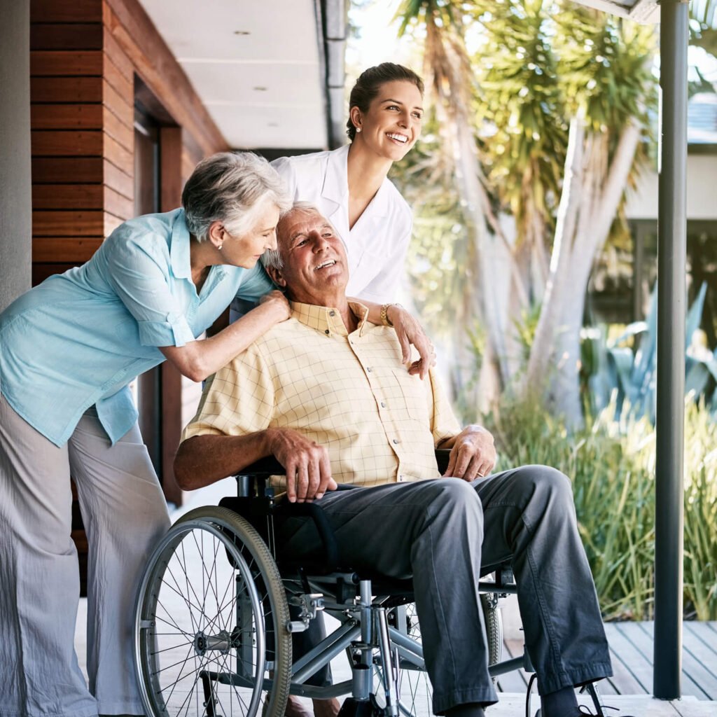 A carer supporting an older couple outdoors
